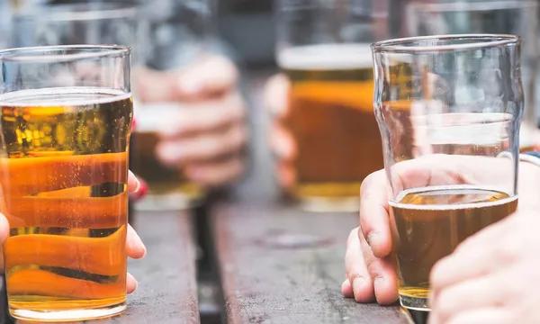 Un groupe d'adolescents est réunit autour d'une table en consommant de la bière.