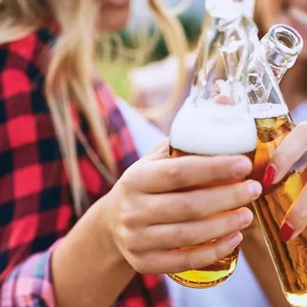 Un groupe de jeunes femmes trinque avec des bouteilles de bière.